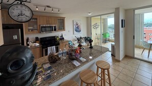 Een moderne keuken met granieten aanrecht, roestvrijstalen apparatuur en een groot eiland met krukken.