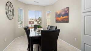 Un comedor con una mesa, sillas, un reloj y un cuadro en la pared.