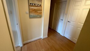 A hallway with wooden flooring, a painting of houses on the wall, and white doors. - 2 bedroom property with a fantastic view of Edinburgh Castle in the heart of the Old Town (Edinburgh)