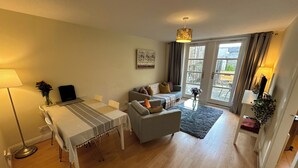 A spacious living area with a dining table, sofa, and a large window providing natural light. - 2 bedroom property with a fantastic view of Edinburgh Castle in the heart of the Old Town (Edinburgh)