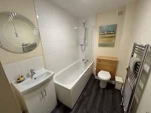 Ein modernes Badezimmer mit Badewanne, Toilette und Waschbecken.