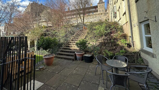 A courtyard with stone steps leading up to a building, surrounded by potted plants and outdoor furniture. - 2 bedroom property with a fantastic view of Edinburgh Castle in the heart of the Old Town (Edinburgh)