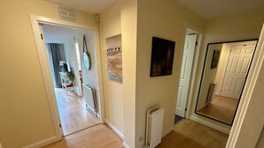 A hallway with wooden flooring, a radiator, and a door leading to another room. - 2 bedroom property with a fantastic view of Edinburgh Castle in the heart of the Old Town (Edinburgh)