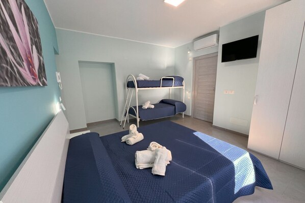 Ein Zimmer mit Etagenbetten, einem Flachbildfernseher und einem Kleiderschrank.