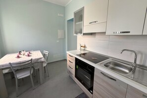 Une cuisine moderne avec une table à manger, des chaises, un four encastré, un évier et des placards.