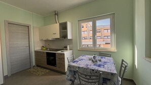 Uma cozinha compacta com área de refeições, uma janela com vista para edifícios e uma porta.