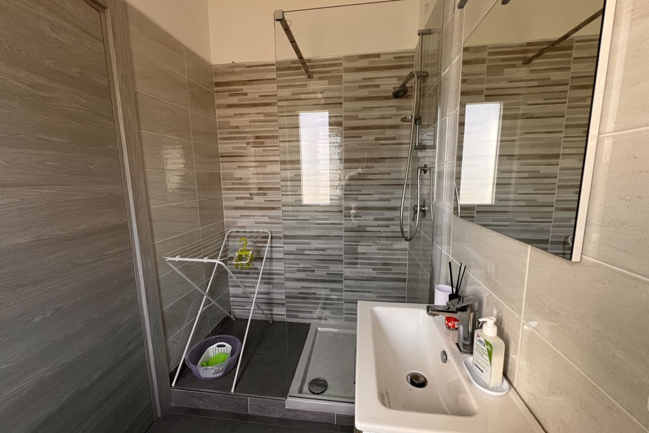 Un bagno moderno con box doccia in vetro, lavandino con articoli da toilette e porta asciugamani.