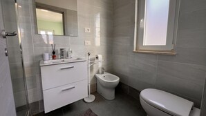 Uma casa de banho moderna com sanita, bidé e toucador branco.