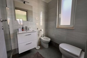 A modern bathroom with a toilet, bidet, and white vanity. - Cozy and modern apartment a stone's throw from the sea (Paola)