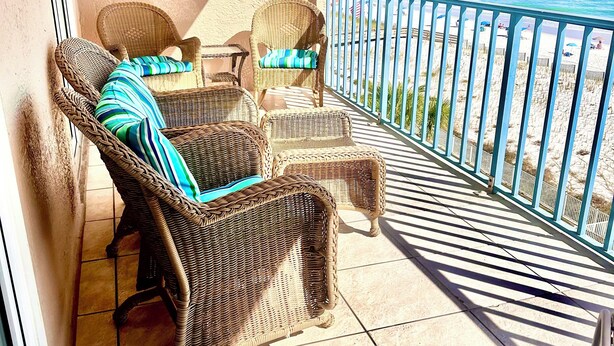 A balcony with wicker furniture, a tiled floor, and a view of the beach. - Direct Beachfront Condo in Gulf Shores/ 2 King Suites/ 2 Pools (Gulf Shores)