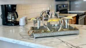 A kitchen counter with a coffee maker, a pitcher, and two glasses on a tray. - Direct Beachfront Condo in Gulf Shores/ 2 King Suites/ 2 Pools (Gulf Shores)
