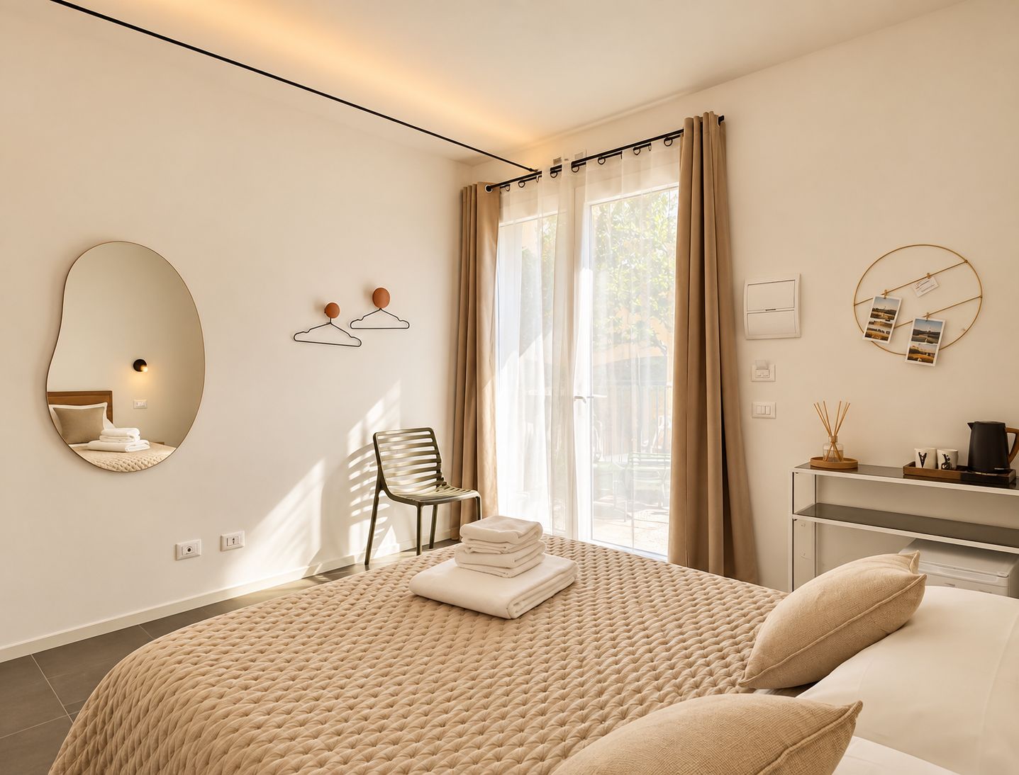 A modern bedroom with a large bed, a chair, a bedside table, a mirror, and a window with curtains.