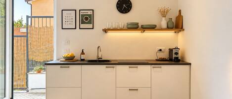 Una cocina moderna con horno integrado, cafetera y un reloj en la pared.
