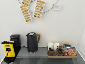 A table with a coffee maker, a tray with mugs and cookies, a yellow bag, and a power strip. - Villa Reise (Riomaggiore)