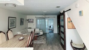 A spacious living area with a dining table, chairs, a sofa, and a ceiling fan.