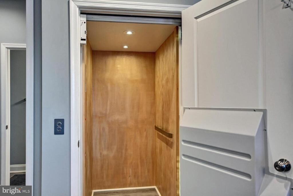 Una habitació amb una porta de fusta, una paret blanca i una porta blanca amb mànec.