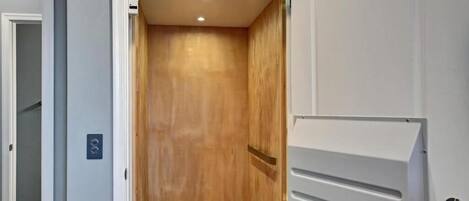 Una habitació amb una porta de fusta, una paret blanca i una porta blanca amb mànec.