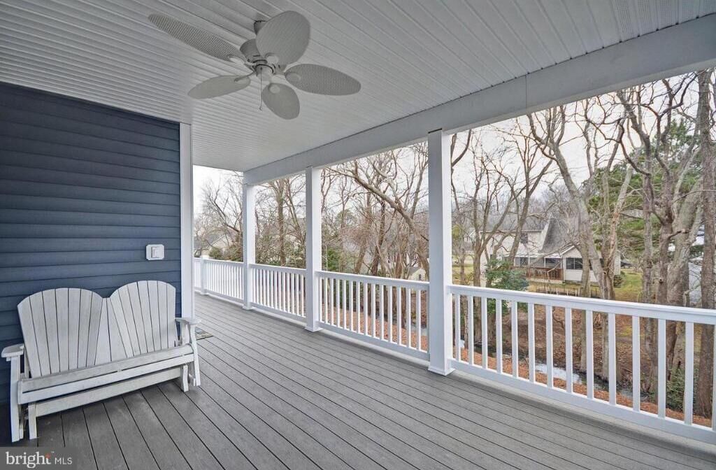 Eine überdachte Veranda mit Deckenventilator, weißer Brüstung und einer Bank.