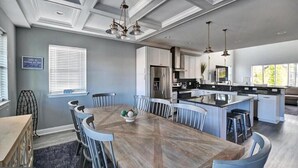A spacious kitchen with a central island, a dining area with a wooden table and chairs, and a view of the outdoors through large windows. - Dream getaway just 2 miles from Fenwick or OC beach.  5BR house sleeps up to 13 (Selbyville)