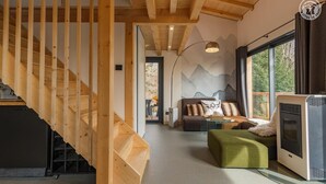 Un intérieur moderne avec un escalier en bois, un ensemble de canapés, une cheminée et de grandes fenêtres donnant sur l ’extérieur.