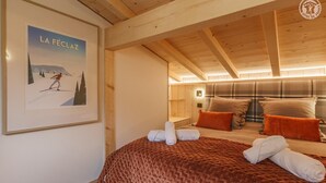 Une pièce chaleureuse avec un plafond en bois, un lit recouvert d’une courtepointe marron, deux oreillers et une affiche accrochée au mur.