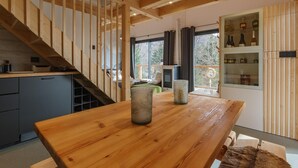 Une table à manger en bois avec deux chandeliers, une cuisine dotée d’un meuble gris et un escalier avec des rampes en bois.