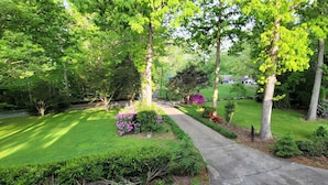 Un jardín bien cuidado con un sendero empedrado, abundante vegetación y diversas plantas en flor.
