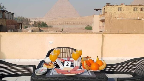 Una mesa al aire libre con vistas a las pirámides al fondo.