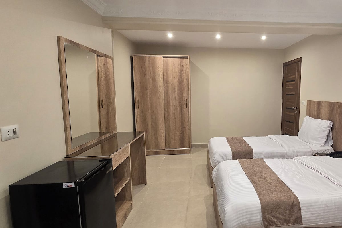 Un dormitorio con dos camas, un armario, un espejo y un escritorio.