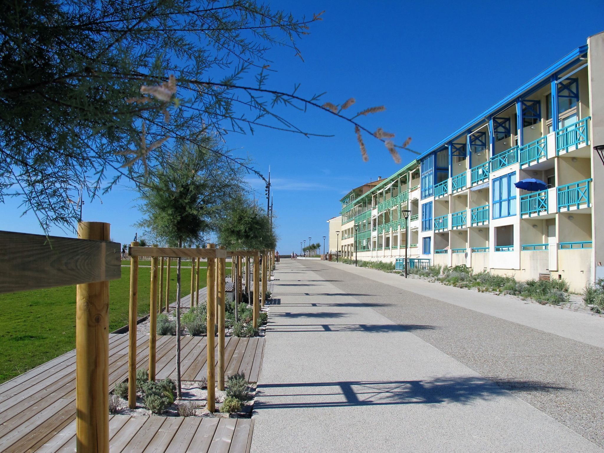 Ett hotell vid kusten med en träpromenad som leder fram till en byggnad med flera balkonger.