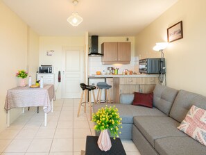 Un espacio habitable compacto con kitchenette, zona de comedor y sala de estar con sofá y mesa baja.