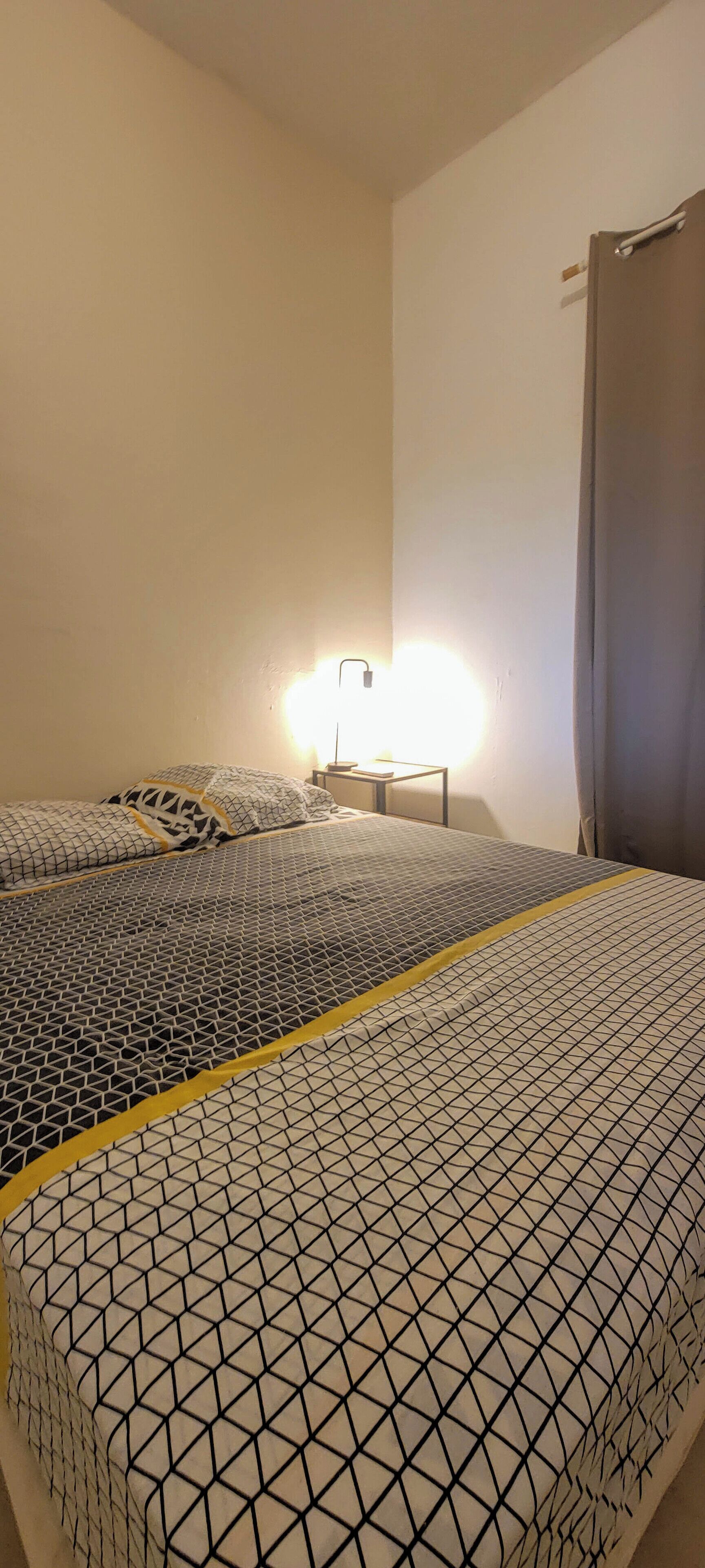 A room with two beds, each with a patterned bedspread and a nightstand with a lamp.