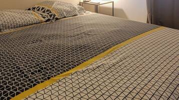 A room with two beds, each with a patterned bedspread and a nightstand with a lamp.