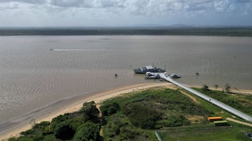 Zona costera con un puente que une dos extensiones de tierra, agua y una pequeña embarcación.