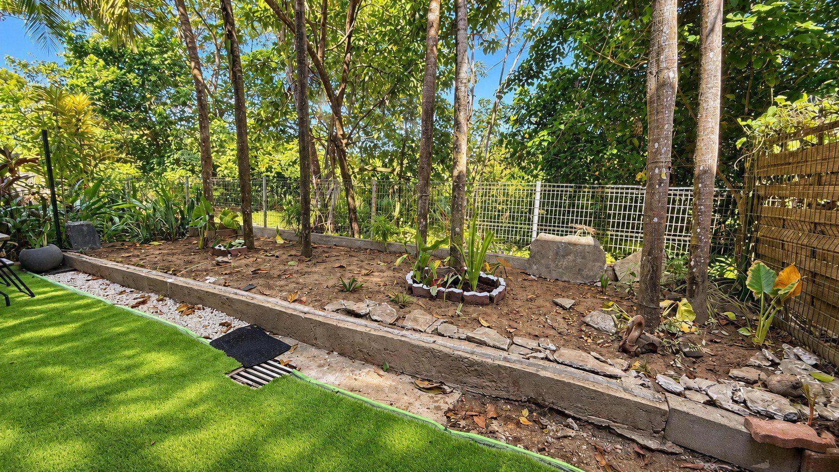 Ein angelegter Garten mit Rasenfläche, einem Kiesweg und unterschiedlichen Pflanzen.
