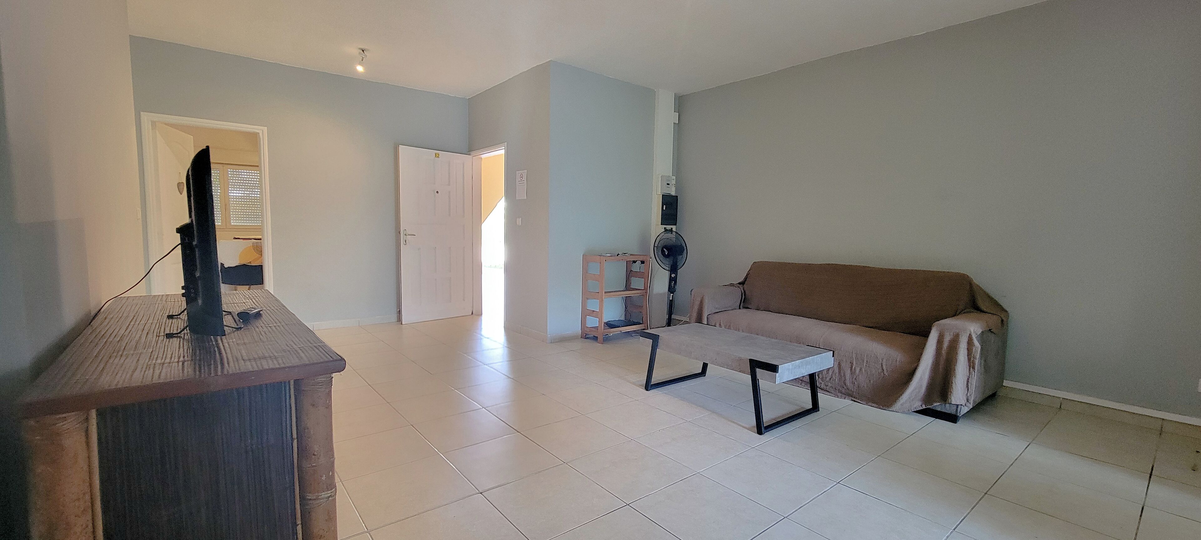 Un amplio salón con un sofá, una mesa de centro y un televisor sobre un mueble.