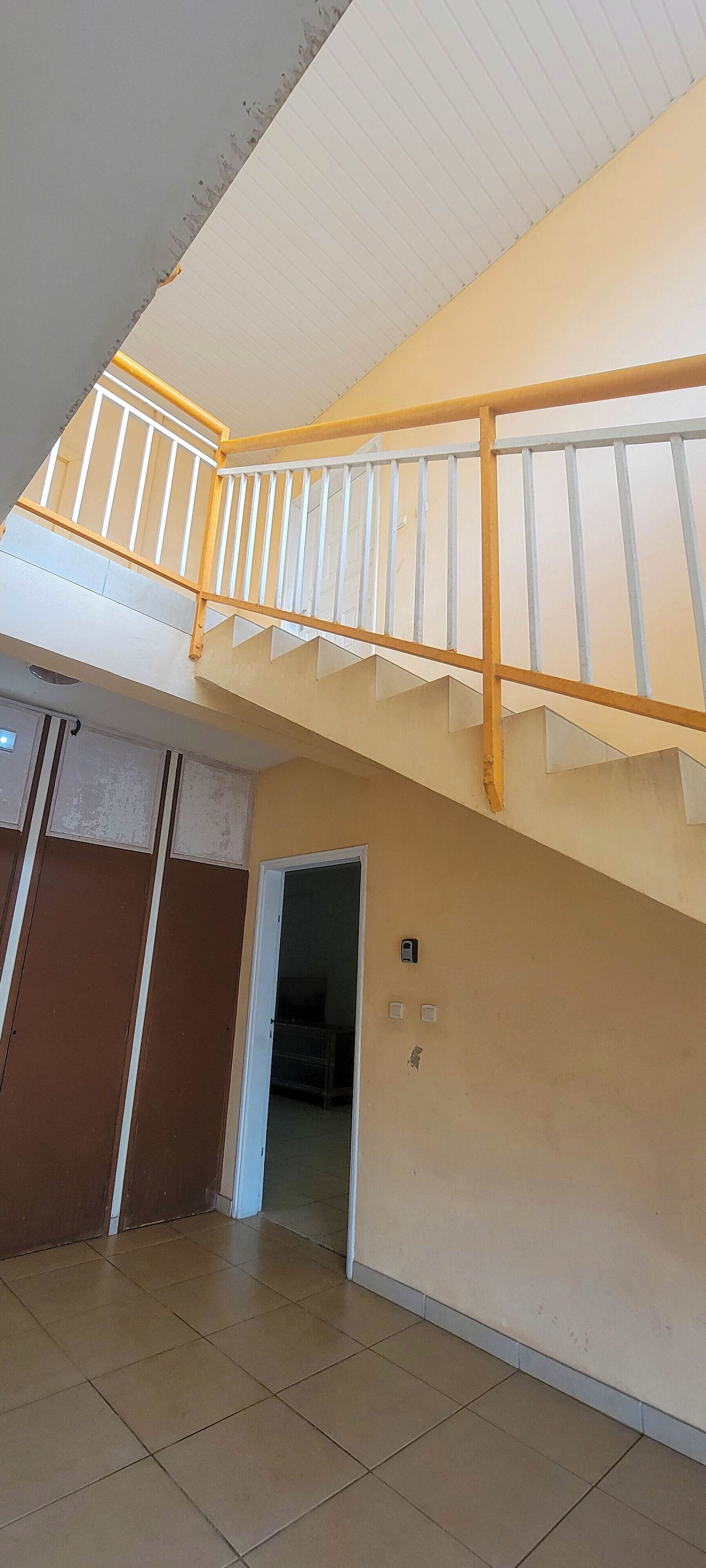 A multi-level interior with a staircase, tiled floors, and a door leading to another room.