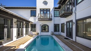 A modern house with a swimming pool, large windows, and a balcony.