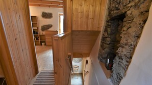 A wooden staircase leading to a loft area with a stone wall and a fireplace. - Dubino Home by Interhome (Valtellina)