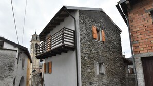 A narrow street with a building featuring a stone facade and a balcony with wooden railings. - Dubino Home by Interhome (Valtellina)