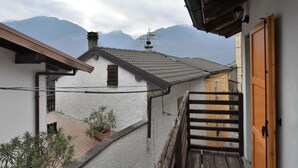 A narrow street with buildings on either side, a wooden gate, and a mountain range in the background. - Dubino Home by Interhome (Valtellina)