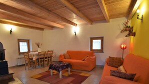A cozy living room with a wooden ceiling, orange sofas, a dining table with chairs, and a fireplace. - Dubino Home by Interhome (Valtellina)
