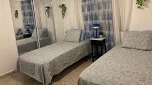 Une chambre avec deux lits, un miroir, une table de chevet, une lampe et une plante en pot.