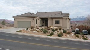 A single-story house with a garage, a front porch, and a landscaped front yard with rocks and shrubs. - King two bedroom apartment with full kitchen and laundry room  (St. George)