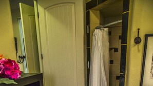 A bathroom with a white door, a shower curtain, a towel rack, and a shelf with folded towels. - King two bedroom apartment with full kitchen and laundry room  (St. George)