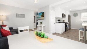 A modern kitchen with white cabinets, stainless steel appliances, and a wooden island with a plant centerpiece.