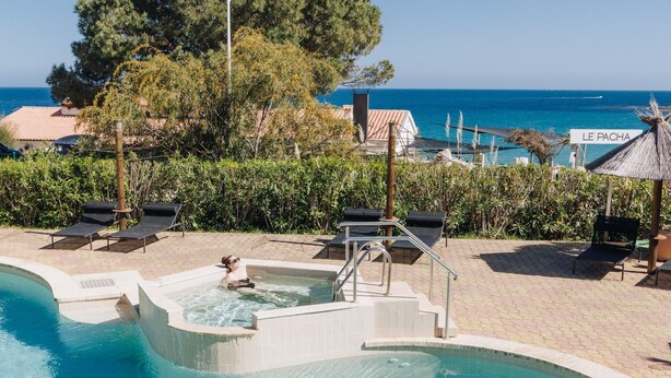 Et poolområde med jacuzzi, liggestole og et skilt med teksten "LE PACHA".