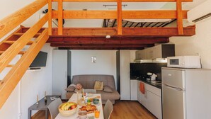Une cuisine compacte avec un coin repas, un canapé et un escalier en bois.
