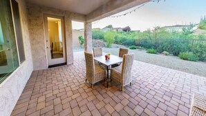 Une terrasse avec un sol en briques et des meubles en osier.