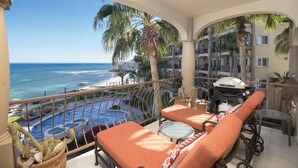 Ein Balkon mit orangefarbenen Sitzmöbeln, ein Pool und Blick aufs Meer.